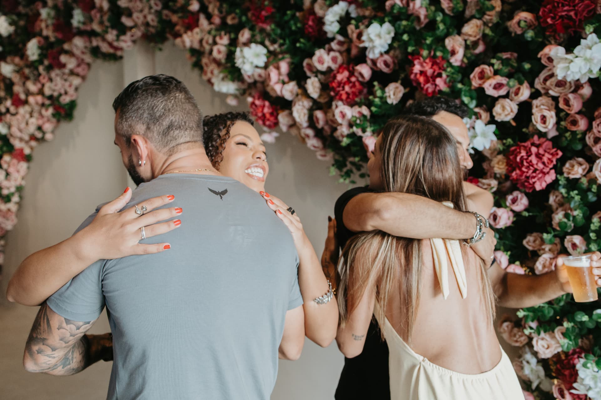 Convidados se abraçando em frente ao painel de flores